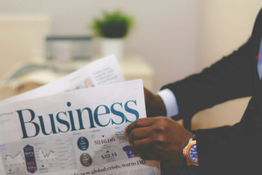 person wearing suit reading business newspaper